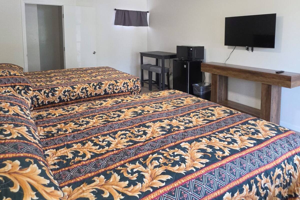 A hotel room with a large bed, a desk, a television, and a door.