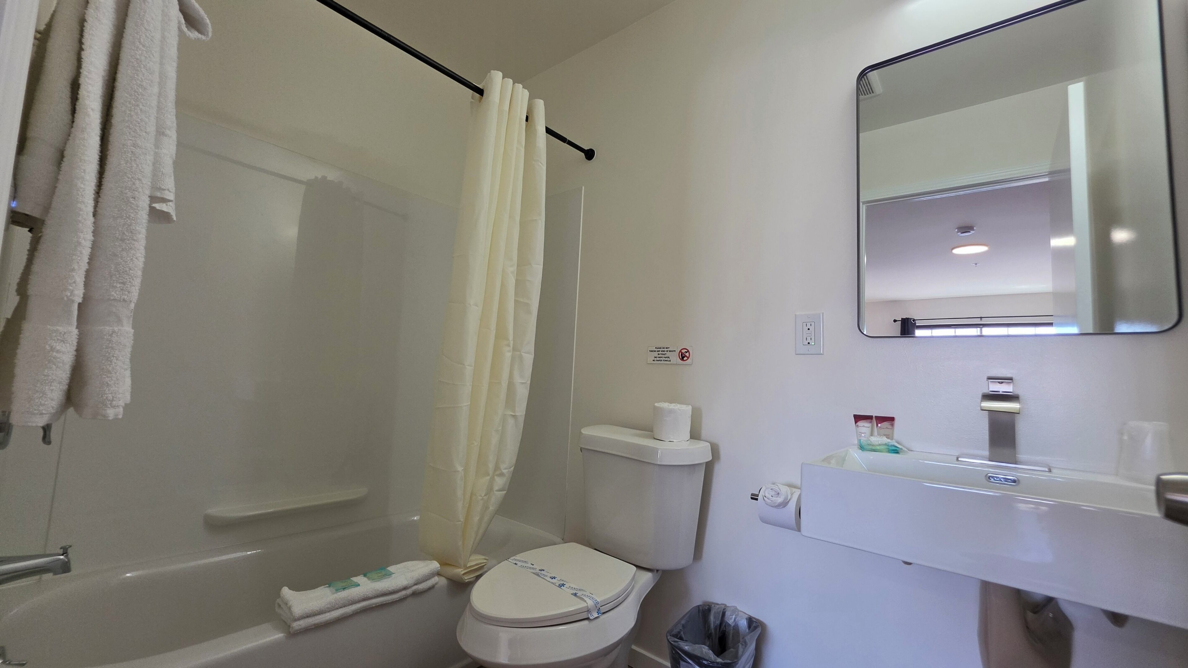 A bathroom with a bathtub, toilet, and a sink with a mirror above it.