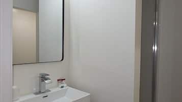A bathroom with a white sink, mirror, and shower.
