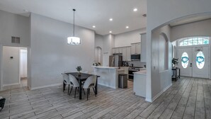 A spacious kitchen with white cabinets, a central island, and a dining area with a table and chairs. - Large 5 bedroom 3 full bath house close to beaches, shopping  and parks. (Parrish)