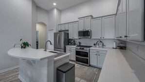 A modern kitchen with white cabinetry, stainless steel appliances, and a central island. - Large 5 bedroom 3 full bath house close to beaches, shopping  and parks. (Parrish)