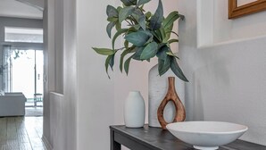 A hallway with a wooden console table holding a white vase, a wooden bowl, and a potted plant. - Large 5 bedroom 3 full bath house close to beaches, shopping  and parks. (Parrish)