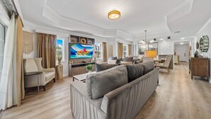 Ein großzügiges Wohnzimmer mit einer großen Couch, einem Fernseher und einer Essecke mit Tisch und Stühlen.