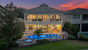 A two-story house with a swimming pool, outdoor seating, and a well-maintained garden. - Homestead Highlands: Pool, Game Room, Theater, Themed, Water Park, Near Disney (Kissimmee)