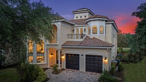 A two-story house with a garage, large windows, and a balcony. - Homestead Highlands: Pool, Game Room, Theater, Themed, Water Park, Near Disney (Kissimmee)
