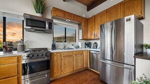 A modern kitchen with wooden cabinets, stainless steel appliances, and a view of the landscape. - Sedona Red Rock Serenity Retreat! (Sedona)