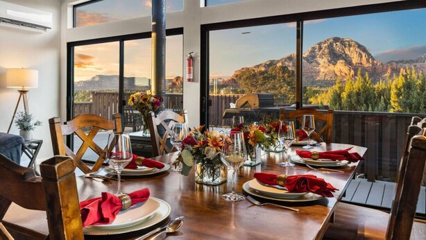 A dining table set for four with a mountain view through large windows. - Sedona Red Rock Serenity Retreat! (Sedona)