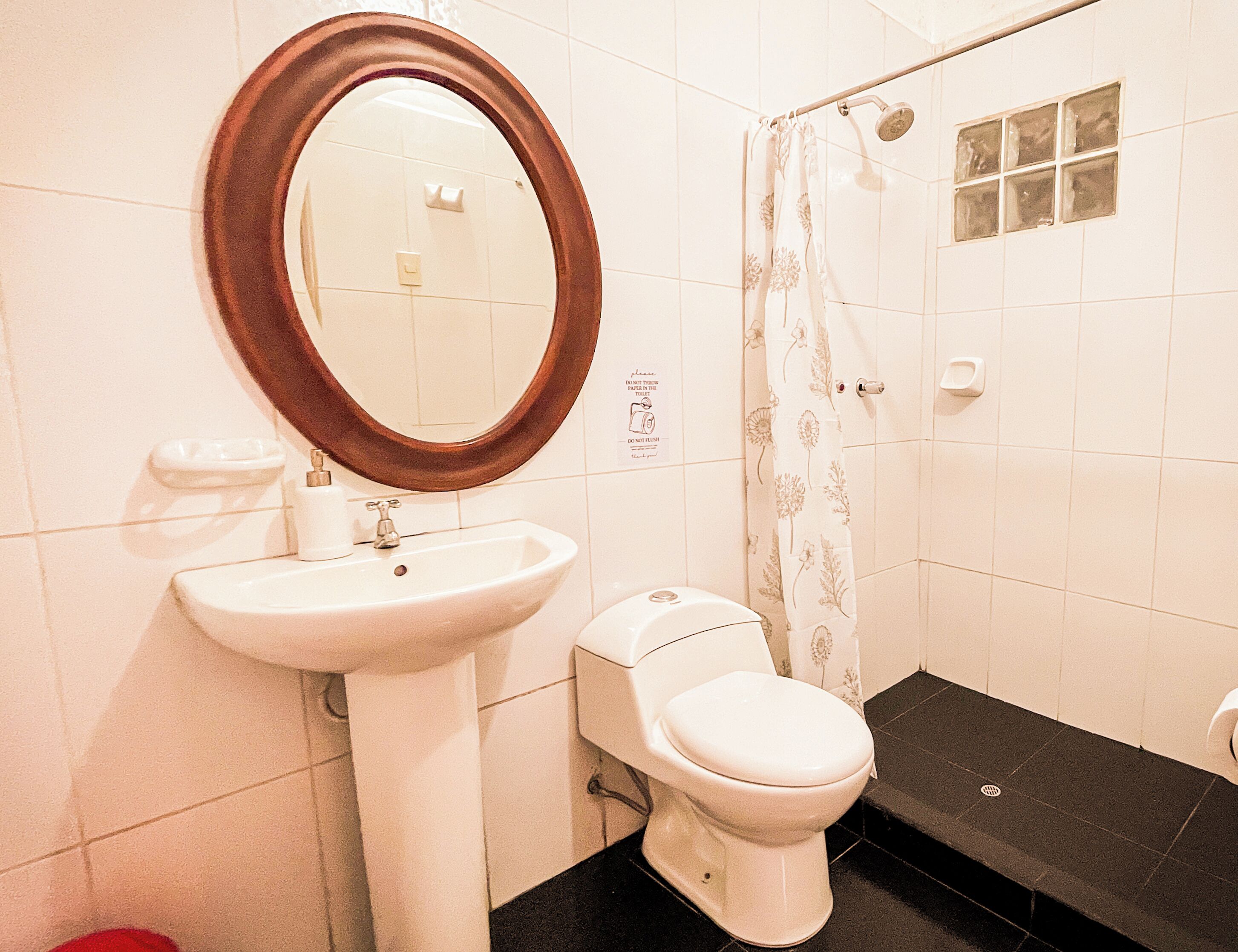 A bathroom with a pedestal sink, toilet, and a shower with a curtain.