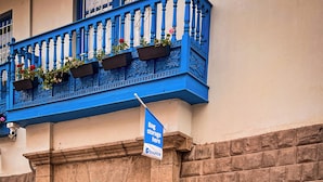 A building with a blue balcony, a sign for bag storage, and a store sign advertising bag storage. - Casa Flamenco San Agustin  (Cusco)