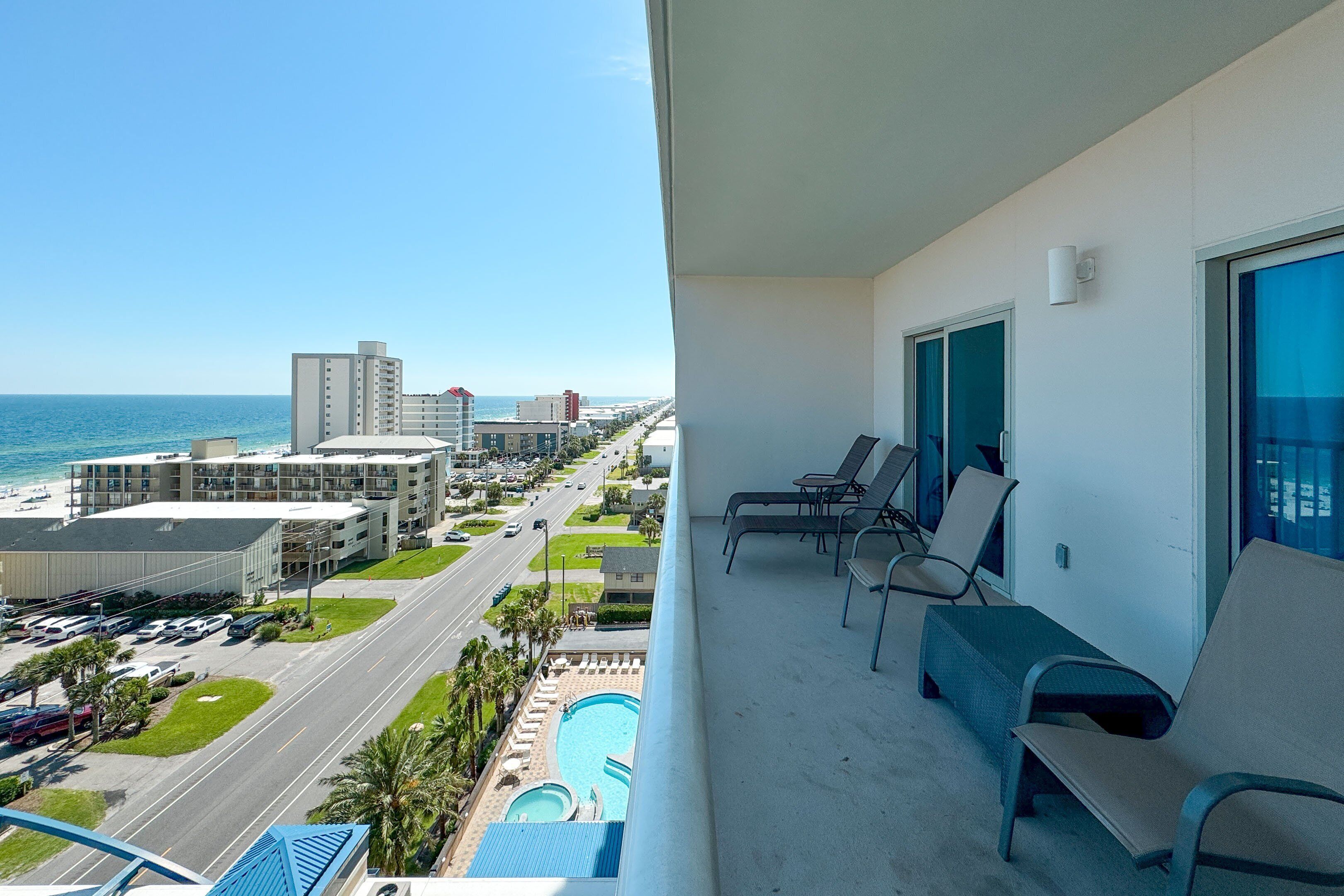 Ein Balkon mit Blick auf einen Pool, eine Straße und Gebäude gegenüber dem Wasser.