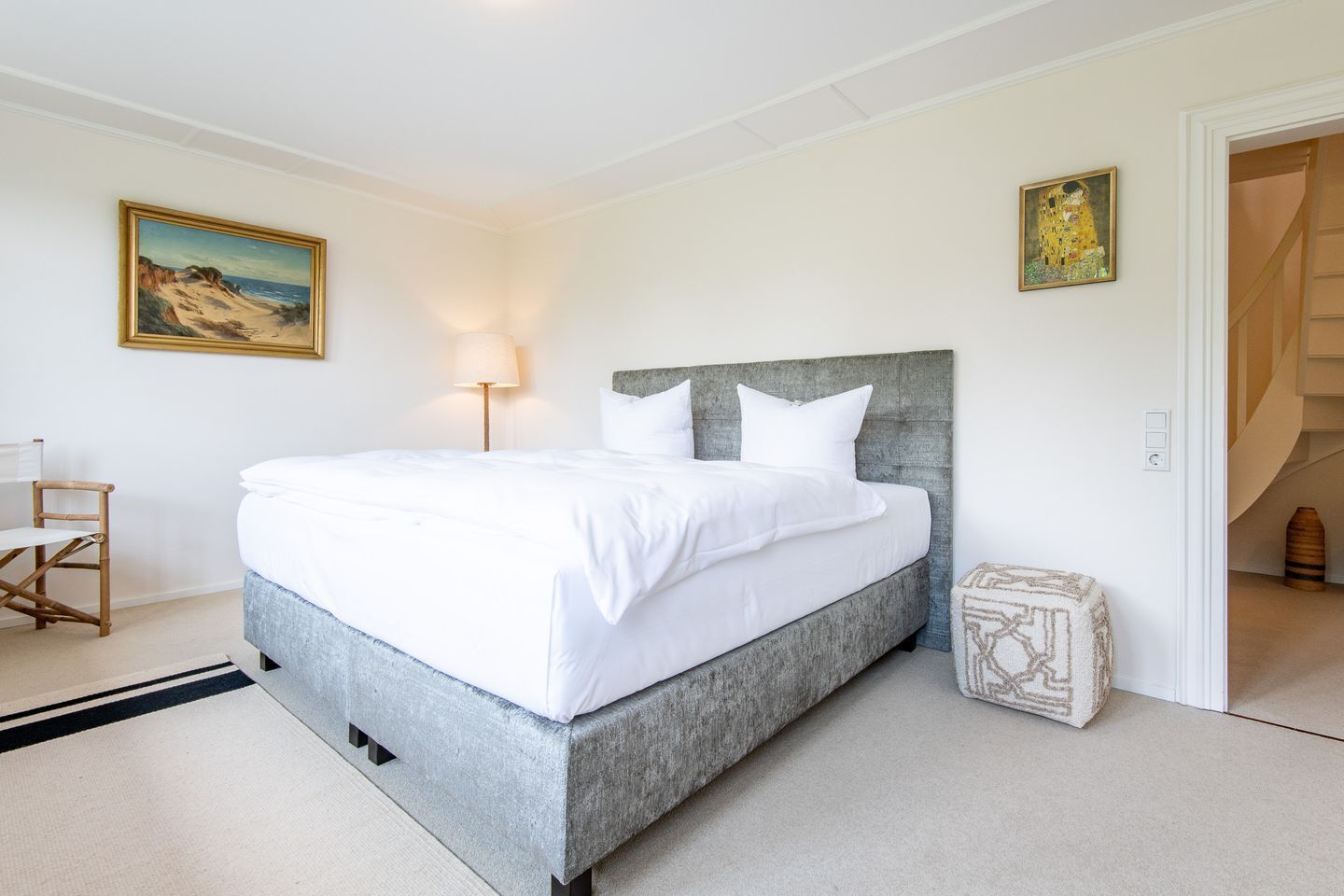 A bedroom with a bed, a nightstand, a lamp, and a painting on the wall.