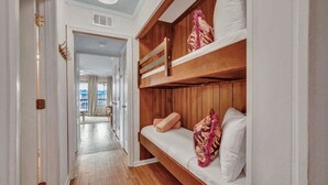Een hotelkamer met een stapelbed, houten vloeren, een gang naar een eethoek en uitzicht op de stad.