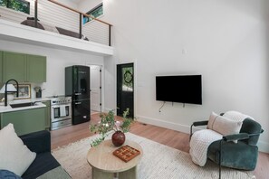 Un salon moderne avec un canapé, une table basse agrémentée d’une plante et un téléviseur fixé au mur.