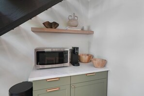 A kitchen with a microwave, coffee maker, and wooden bowls on the counter.