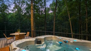 A hot tub on a wooden deck surrounded by a forest. - Uckor's Edge | Hocking Hills, Modern Cozy Cabin (Rockbridge)