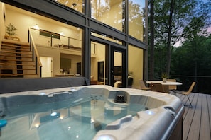 A hot tub on a wooden deck with a view of a modern house and trees. - Uckor's Edge | Hocking Hills, Modern Cozy Cabin (Rockbridge)