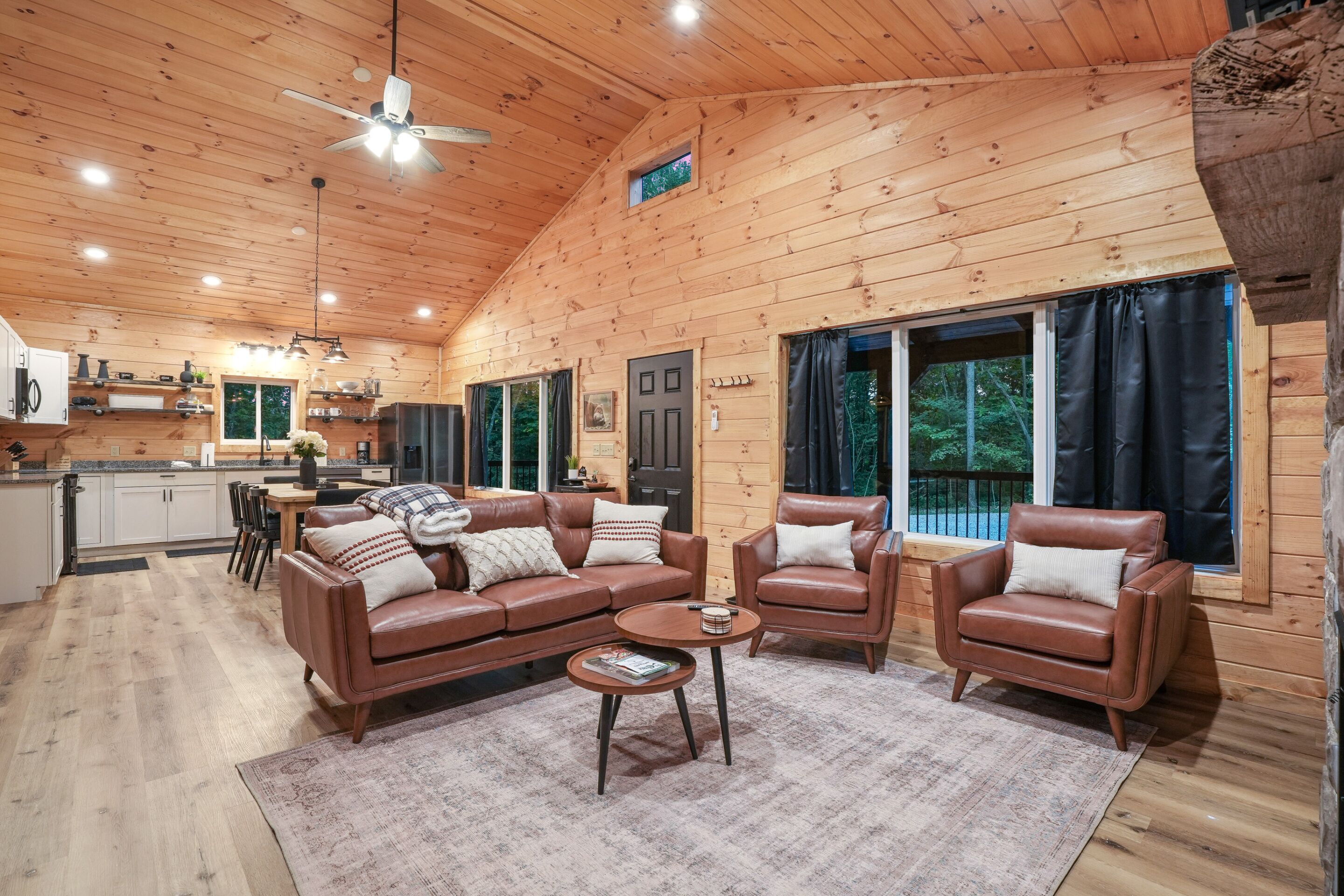 A wooden cabin interior with a living room, kitchen, and dining area.