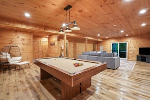 Un interno in legno con tavolo da biliardo, divano e televisore.