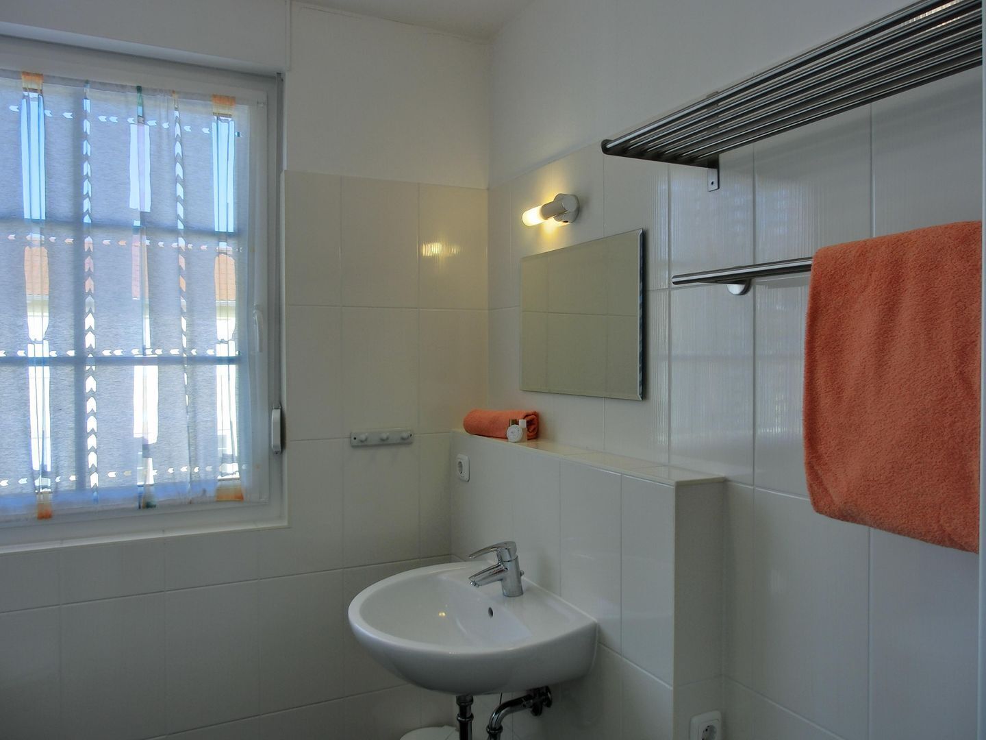 A bathroom with a white sink, a mirror, and a towel rack.