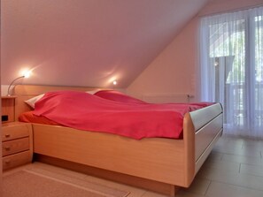 A bedroom with a bed, bedside tables, and a window with curtains.