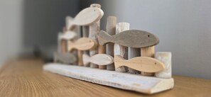 Una escultura de madera de pez sobre un estante rústico.