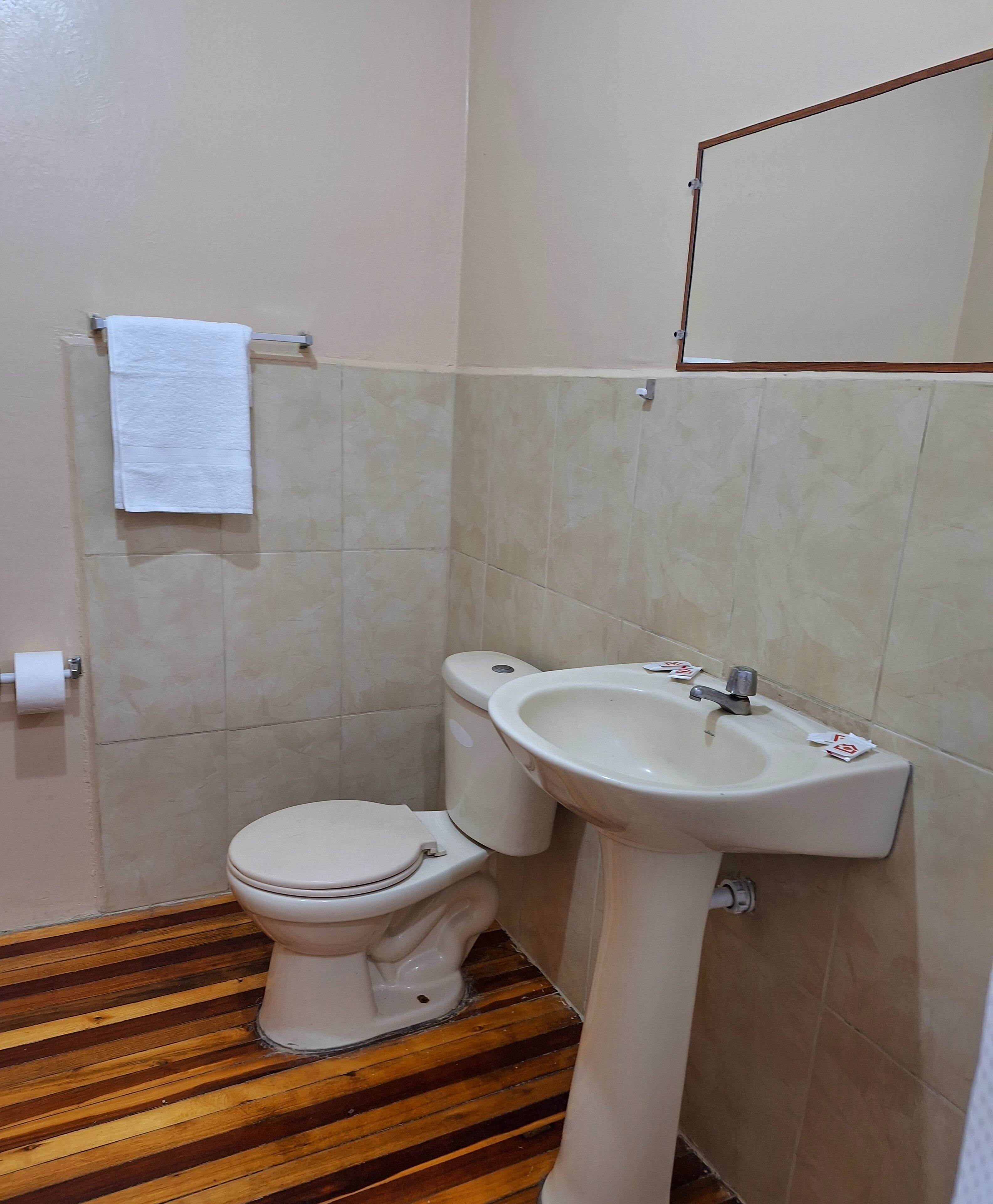 Un bagno piccolo con il water, un lavandino e un pavimento in legno.