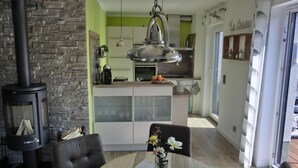 A modern kitchen with a central island, a dining area with a table and chairs, and a stone wall. - Ferienwohnung Lp24 - Strandnahe 2-zi.-fewo für 2 Pers.- im 4. OG in Ruhiger Lage (Graal-Müritz)