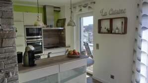 A modern kitchen with a stone accent wall, a built-in oven, and a wooden countertop. - Ferienwohnung Lp24 - Strandnahe 2-zi.-fewo für 2 Pers.- im 4. OG in Ruhiger Lage (Graal-Müritz)