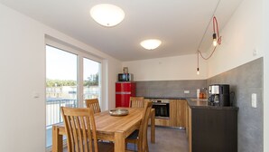 Una cucina moderna con zona pranzo, caratterizzata da un tavolo e sedie in legno, un frigorifero rosso e una macchina da caffè.