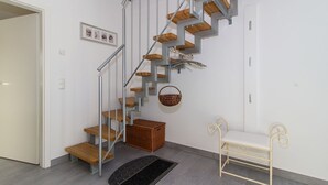 Una moderna scala con gradini in legno e ringhiere metalliche, una panca, un cesto e un tavolino.