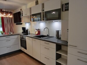 Cocina moderna con encimera negra, electrodomésticos de acero inoxidable y armarios blancos.