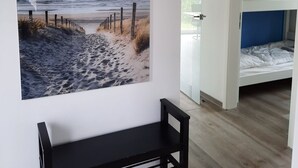 Una habitación con literas, un estante en la pared y un cuadro con una escena de playa.