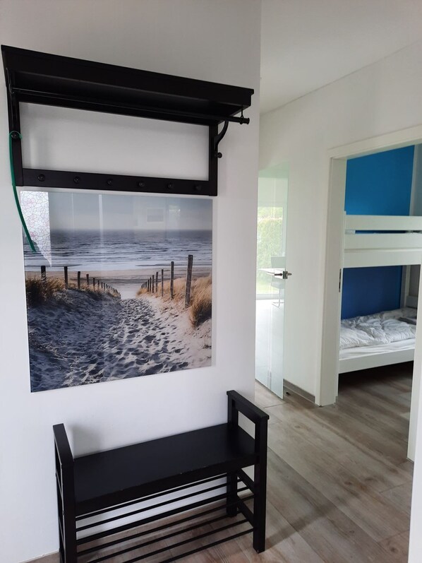 Una habitación con literas, un estante en la pared y un cuadro con una escena de playa.