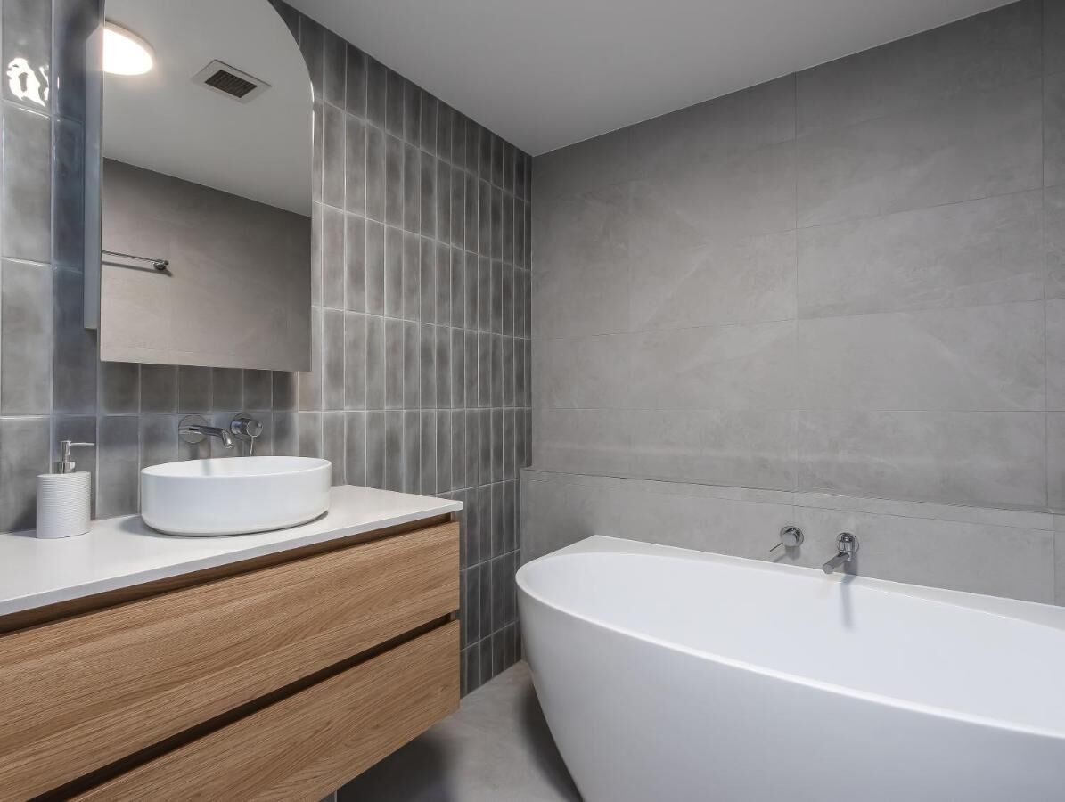 Une salle de bain moderne avec une baignoire sur pieds, un lavabo rond et un meuble-lavabo en bois.