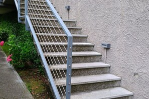 Un escalier en béton, doté d’une rampe métallique, mène à l’entrée d’un immeuble.