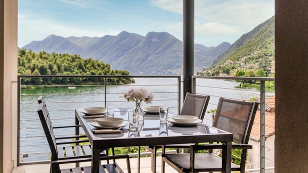 A balcony table with chairs, a vase with flowers, and a view of mountains and a lake. - Lake's Dream - MyHomeinComo (Ossuccio)