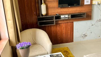 Deluxe kamer | Woonruimte | Ledtelevisie, een open haard, een videogameconsole en betaalfilms