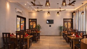 Ein Restaurant mit Holztischen und -stühlen, Deckenventilatoren und einem an der Wand befestigten Fernseher.