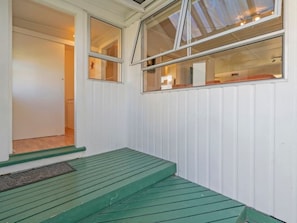 A room with a green wooden bench, white walls, and a window with a view of the interior.