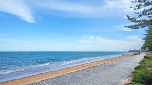 Un paseo marítimo de madera que conduce a una playa con cielos despejados.