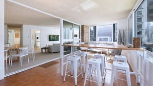 Un espacio habitable moderno con cocina, comedor y ventanas amplias.
