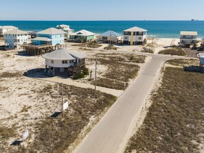 Una zona costiera con case sulla spiaggia, una strada e un molo.