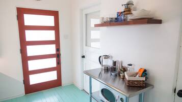 A kitchen with a red door, a coffee maker, a kettle, and a microwave.