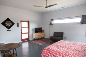 Une chambre à coucher comprenant un lit, un bureau, une chaise, une télévision, une armoire, une fenêtre et un ventilateur de plafond.