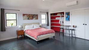 A bedroom with a bed, bedside tables, a ceiling fan, a window with curtains, a red and white bookshelf, and a small table with chairs. - La Cochera Private Apartment - No Cleaning Fee (Alpine)