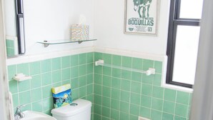A bathroom with a toilet, sink, and a trash can. There is a sign on the wall that says "VISIT BUQUILLAS." - La Cochera Private Apartment - No Cleaning Fee (Alpine)