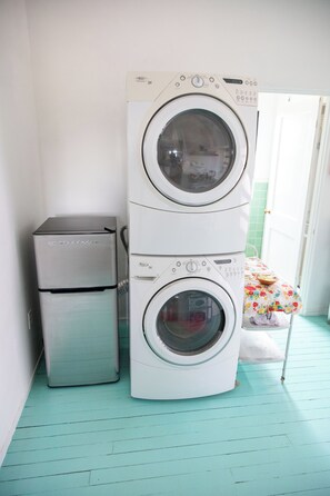 Un área de lavandería con lavadoras apiladas y un refrigerador.