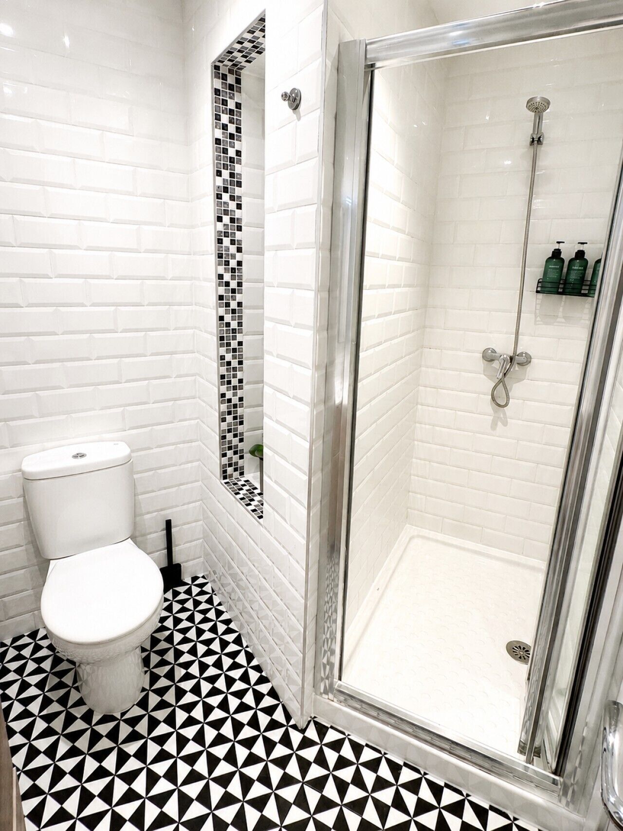 Ein Badezimmer mit Toilette, einer Duschkabine mit Glastür und Fliesenboden.
