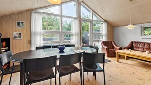 Una habitación amplia con una gran mesa de comedor, varias sillas, un sofá de cuero marrón y un banco de madera.