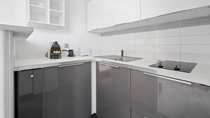 A modern kitchen with white cabinetry, a stainless steel sink, and a built-in oven.